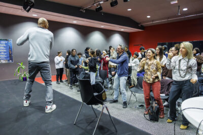 Aurelien Duarte sur la scène du Virtuoz Club de Villeneuve-la-Garenne tient dans sa main un micro pour présenter sa conférence. - Agrandir l'image 4 sur 6, fenêtre modale