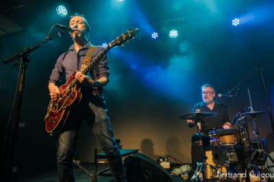Un des chanteurs du groupe Les Innocents joue de la guitare sur la scène du Virtuoz club de Villeneuve-la-Garenne - Agrandir l'image 2 sur 6, fenêtre modale