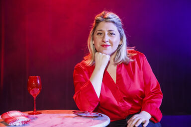 Marion Mézadorian, humoriste, est sur la scène du cinéma André-Malraux pour son spectacle craquage. Elle est accoudée sur une table.