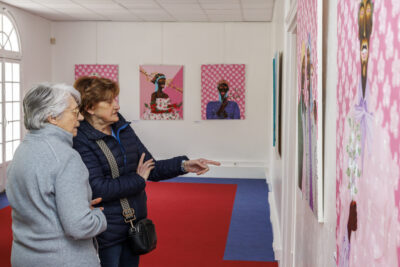 Deux femmes regardent les tableaux de l'artiste Jules Be Kuti lors du vernissage de l'exposition qui lui est consacré à Villeneuve-la-Garenne. - Agrandir l'image 3 sur 6, fenêtre modale