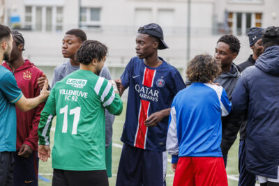 Plusieurs hommes se serrent la main sur un terrain de foot et avant de disputer un match dans le cadre du tournoi de foot Borriello de la ville de Villeneuve-la-Garenne - Agrandir l'image 5 sur 6, fenêtre modale