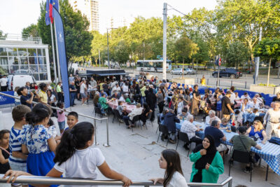 Plusieurs habitants sont réunis sur les tables et dégustent les différents plats des food trucks dans le cadre de la soirée food trucks et musique de Villeneuve-la-Garenne. - Agrandir l'image 3 sur 6, fenêtre modale