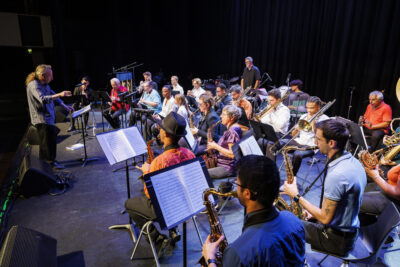 Un maître d'orchestre guide plusieurs jeunes sont sur scène en train de jouer d'un instrument dans le cadre du gala de fin d'année de l'école de musique Claude-Debussy à Villeneuve-la-Garenne. - Agrandir l'image 6 sur 6, fenêtre modale