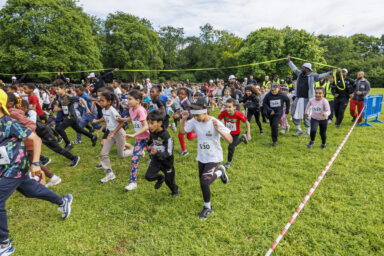 Plusieurs élèves des écoles de Villeneuve-la-Garenne sont en train de courir pour la course Mil'Pattes dans un parc de la ville.