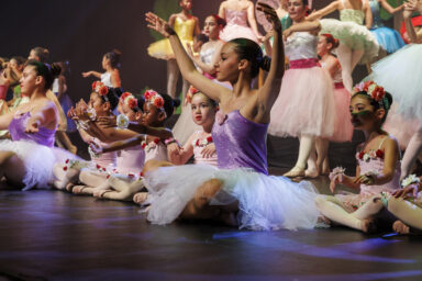 Une jeune fille lève les bras gracieusement habillée d'un tutu au gala de danse de Villeneuve-la-Garenne.