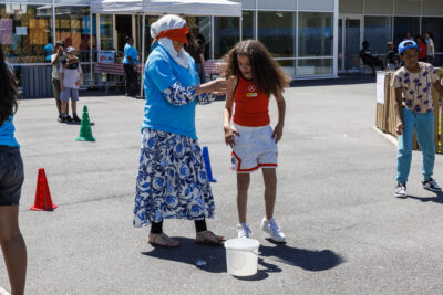 Une dame a les yeux bandés et sa fille l'aide à avancer dans un jeu dans le cadre de la fête des accueils de loisirs. - Agrandir l'image 5 sur 6, fenêtre modale
