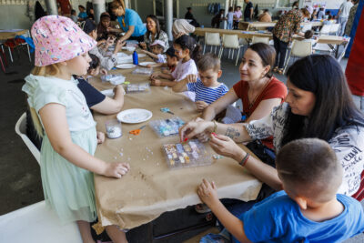 Des enfants avec leur parents sont en train de faire un atelier peinture à la fête des accueils de loisirs de Villeneuve-la-Garenne - Agrandir l'image 2 sur 6, fenêtre modale