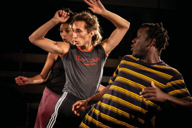 trois jeunes sont en train de faire des pas de danse sur une scène
