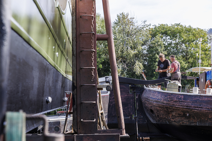 Deux hommes sont en train de réparer un bateau sur les chantiers navals de Villeneuve-la-Garenne