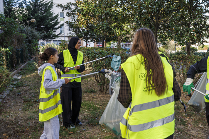 3 jeunes filles sont en train de nettoyer un espace vert avec leur pince. Elles ramassent des déchets dans le cadre du clean challenge de Villeneuve-la-Garenne.
