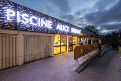 L'entrée principale de la piscine municipale avec l'inscription lumineuse "Piscine Alice Milliat". - Agrandir l'image 6 sur 7, fenêtre modale