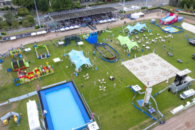 Vu d'un drone du village olympique tenu dans un stade avec une piscine, des structures gonflable et des transats. - Agrandir l'image 5 sur 6, fenêtre modale