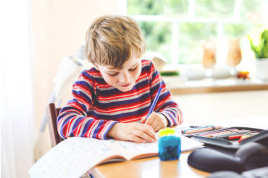 Petit garçon qui est en train d'écrire sur un cahier
