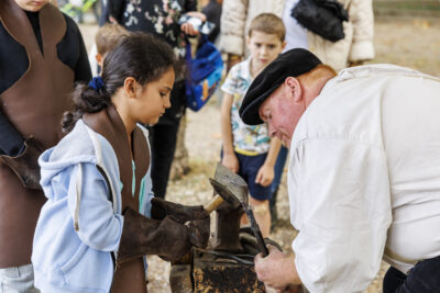 Un homme qui présente un atelier de ferronnerie à des enfants - Agrandir l'image 4 sur 6, fenêtre modale