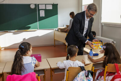 Un homme distribue des fourniture scolaire à des enfants dans une classe - Agrandir l'image 5 sur 6, fenêtre modale