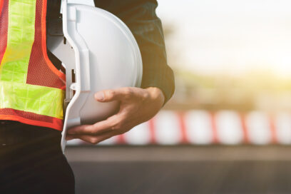homme qui tient un casque de chantier dans sa main vêtu d'un gilet orange - Agrandir l'image, fenêtre modale