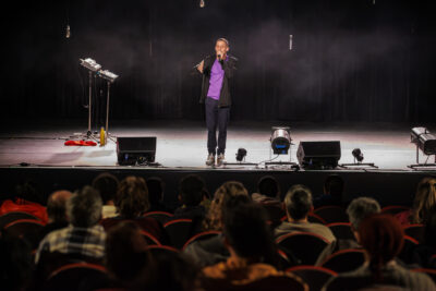 L'humoriste Kosh sur scène avec un micro - Agrandir l'image 4 sur 6, fenêtre modale