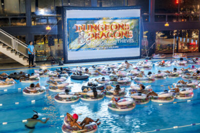 Plusieurs personnes sont assis dans une bouée gonflable à la piscine municipale de Villeneuve-la-Garenne face à un écran géant pour regarder un film à l'événement ciné piscine - Agrandir l'image 5 sur 6, fenêtre modale