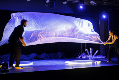 Les deux artistes interagissent sous une grande structure translucide éclairé en bleu - Agrandir l'image 3 sur 6, fenêtre modale